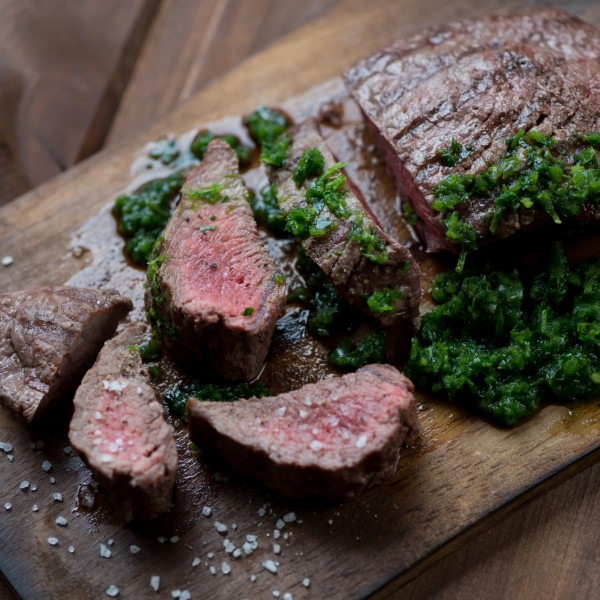 Medium rare grilled beef steak with chimmichurri sauce, close-up